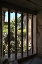 An outside view from a window secured with iron bars revealing rural India.