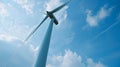 On the outskirts of a rural town a windmill towers over the landscape its large blades turning gracefully in the breeze