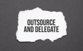 outsource and delegate sign on the torn paper on the black background