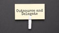 outsource and delegate text on paper with wihte clip. On black background Royalty Free Stock Photo