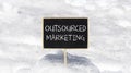 Outsourced marketing symbol. Concept words Outsourced marketing on beautiful black chalk blackboard. Beautiful white snow