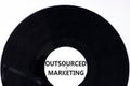Outsourced marketing symbol. Concept words Outsourced marketing on beautiful black vinyl disk. Beautiful white table white
