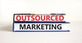 Outsourced marketing symbol. Concept words Outsourced marketing on beautiful books. Beautiful white table white background.
