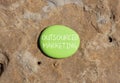 Outsourced marketing symbol. Concept words Outsourced marketing on beautiful green stone. Beautiful red stone background. Business