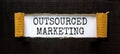 Outsourced marketing symbol. Concept words Outsourced marketing on beautiful white paper. Beautiful black paper background.