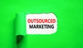Outsourced marketing symbol. Concept words Outsourced marketing on beautiful white paper. Beautiful green paper background.