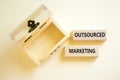 Outsourced marketing symbol. Concept words Outsourced marketing on beautiful wooden blocks. Beautiful white table white background