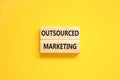 Outsourced marketing symbol. Concept words Outsourced marketing on beautiful wooden blocks. Beautiful yellow table yellow
