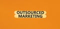 Outsourced marketing symbol. Concept words Outsourced marketing on beautiful wooden stick. Beautiful orange table orange