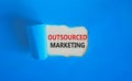 Outsourced marketing symbol. Concept words Outsourced marketing on beautiful white paper. Beautiful blue paper background.