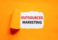 Outsourced marketing symbol. Concept words Outsourced marketing on beautiful white paper. Beautiful orange paper background.