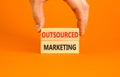 Outsourced marketing symbol. Concept words Outsourced marketing on beautiful wooden blocks. Beautiful orange table orange