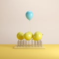 Outstanding blue balloon floating with yellow balloons above nail traps on yellow pastel background Royalty Free Stock Photo