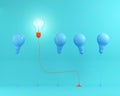 Outstanding red light bulbs with glowing in air one different idea from light bulbs the others on blue pastel background,Minimal Royalty Free Stock Photo