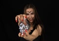 On outstretched arms on Halloween night, a laughing witch holds a glass skull in the dark. Studio shot. Portrait. A Royalty Free Stock Photo