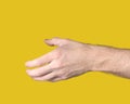 Outstretched male hand with open palm ready to shake other hand on yellow background. Gesture to reach out or take something.