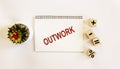 OUTWORK , the text is written on a notebook and a white background. On the table are wooden cubes with signs and there is a cactus Royalty Free Stock Photo