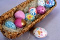 Oval basket full of brightly colored Easter eggs with one white spotted egg beside Royalty Free Stock Photo