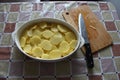 Oval ceramic dish with sliced potatoes and knife near Royalty Free Stock Photo