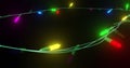 Oval of coloured christmas string lights flashing on black background, copy space
