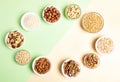 Oval frame of bowls with cereal grains and nuts on two-tone beige-green backdrop. Top view Royalty Free Stock Photo