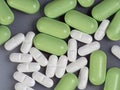 Oval green and white pills in bulk on a gray background. Close-up. Medical background with medications. View from above. Royalty Free Stock Photo