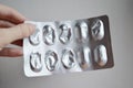 Oval medical tablets in pack, tablets packed in blisters. Partly used package in woman`s hand