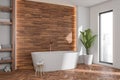 Oval white bathtub in modern bathroom with wood look tiles. Corner view Royalty Free Stock Photo