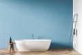 Oval white ceramic bathtub with minimalist design in blue bathroom background Royalty Free Stock Photo