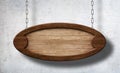 Oval wooden sign hanging on chains with concrete wall background Royalty Free Stock Photo