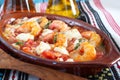 Oven backed prawns with feta, tomato, paprika, thyme in a traditional ceramic form on a abstract background. Healthy