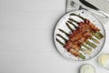 Oven baked asparagus wrapped with bacon on wooden table, flat lay. Space for text Royalty Free Stock Photo