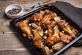 Oven baked chicken legs with onions, garlic and a mixture of peppers on dark wooden background closeup. Top view with copy space Royalty Free Stock Photo