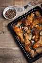 Oven baked chicken legs with onions, garlic and a mixture of peppers on dark wooden background closeup. Top view with Royalty Free Stock Photo