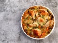 Oven Baked Chicken and Rice with onions, carrots and herbs in a white baking dish on a dark grey background
