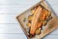 Oven baked half salmon filled with lemon, garlic, thyme on a baking tray on white background with space for text. Flat lay Royalty Free Stock Photo