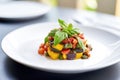 oven-baked ratatouille garnished with basil on white plate