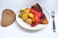 oven grilled bacon slices with delicious curry sauce served on white plate, baked potatoes with meat, red paprika, green capsicum Royalty Free Stock Photo