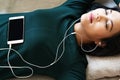 Over head view of beautiful young woman laying down on sofa using smartphone to listen the music Royalty Free Stock Photo