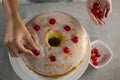 Woman toping a fresh baked cake with cherry