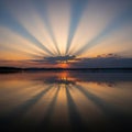 Over a serene lake, with dramatic crepuscular rays emanating Royalty Free Stock Photo