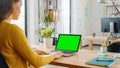 Over the Shoulder: Creative Young Woman Sitting at Her Desk Using Laptop with Mock-up Green Screen Royalty Free Stock Photo