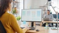 Over the Shoulder: Female Mobile Software Developer Sitting at Her Desk Using Desktop Computer wit
