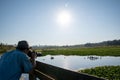 An over-the-shoulder shot of an Asian man with a hat and sunglasses who is taking a photo of some birds.