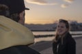 Over the shoulder shot of guy in yellow hood jacket to smiling woman blurry Royalty Free Stock Photo