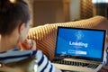 Healthy woman looking at computer loading screen on laptop