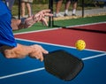 Over the shoulder shot of man hitting a pickleball with a paddle