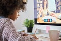 Over shoulder view of black pupil sitting learning online at home with tutor.