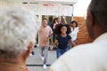 Over shoulder view of family running to welcome grandparents for a surprise family party