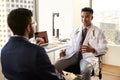 Over The Shoulder View Of Man Having Consultation With Male Doctor In Hospital Office Royalty Free Stock Photo